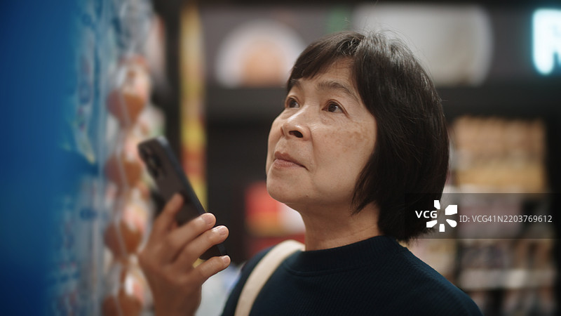 成熟的女性在超市购物时与聊天机器人交谈。图片素材