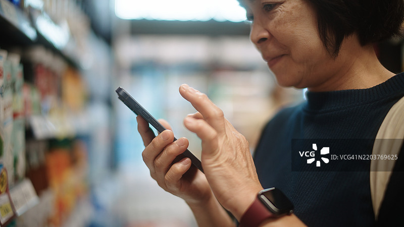 成熟的女性在超市购物时与聊天机器人交谈。图片素材
