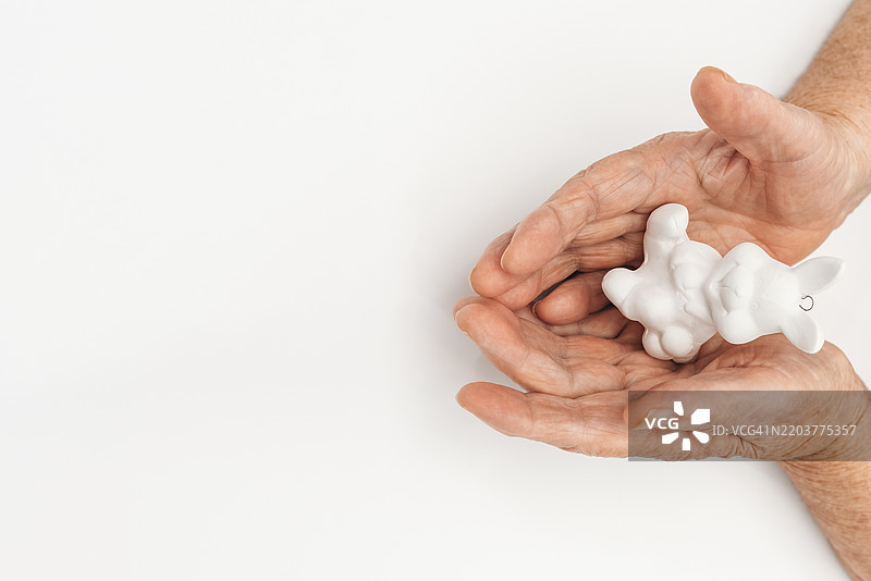 白色背景上老年女性手中的兔子图片素材