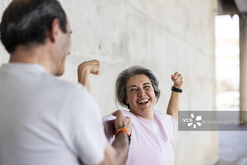快乐的老年女性与她的私人教练展示肌肉图片素材