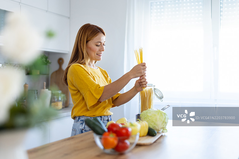 快乐的女性在时尚厨房中处理干意大利面图片素材