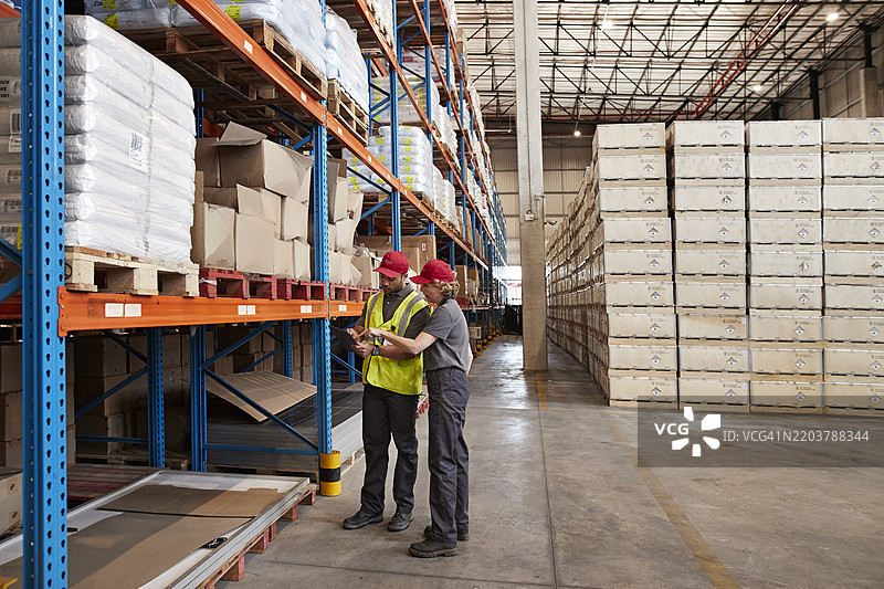 女性员工在仓库与同事讨论图片素材