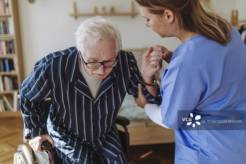 家庭护理人员在家中协助老年男性图片素材