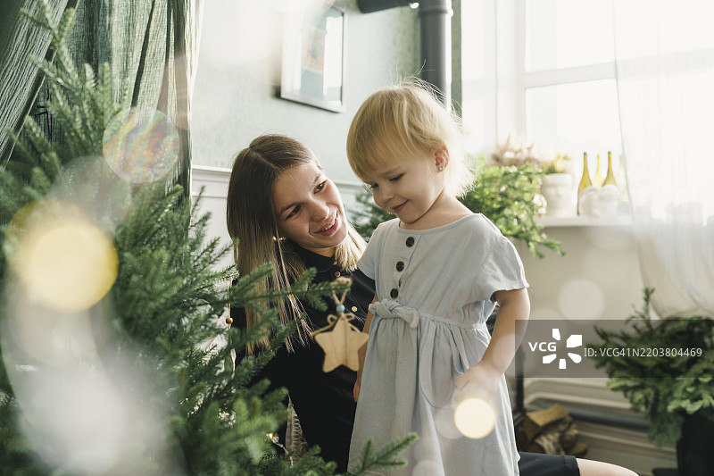 快乐的母女在家里装饰圣诞树图片素材