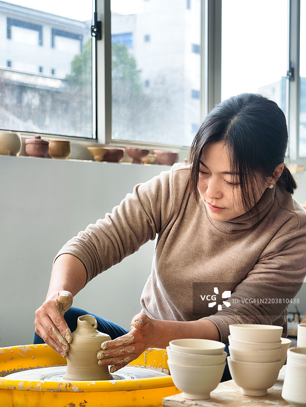 女陶艺师正在陶轮上制作花瓶图片素材