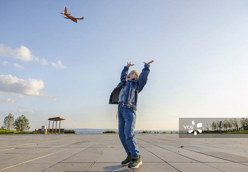 无忧无虑的男孩在天空下抓玩具飞机图片素材