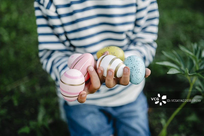 男孩的手握着五彩斑斓的复活节彩蛋图片素材