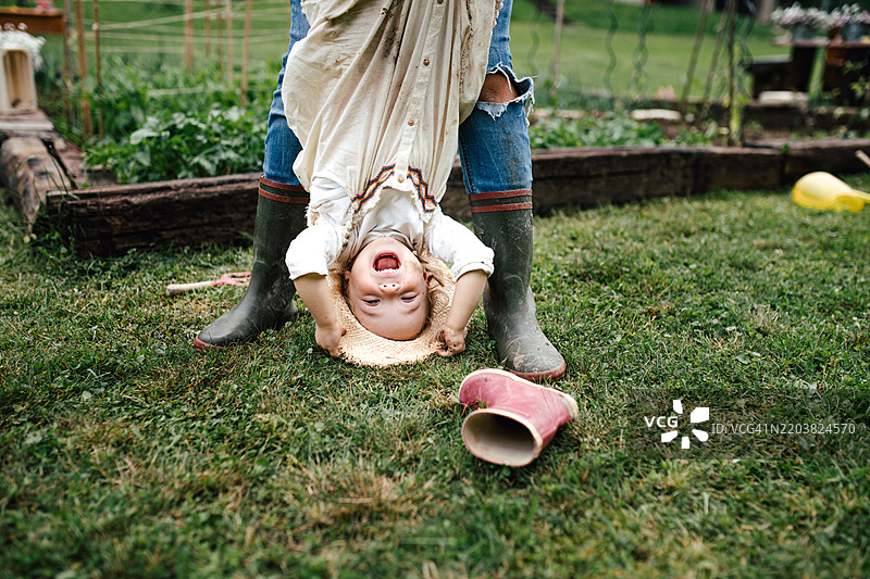 家长顽皮地把小女孩倒提着。图片素材