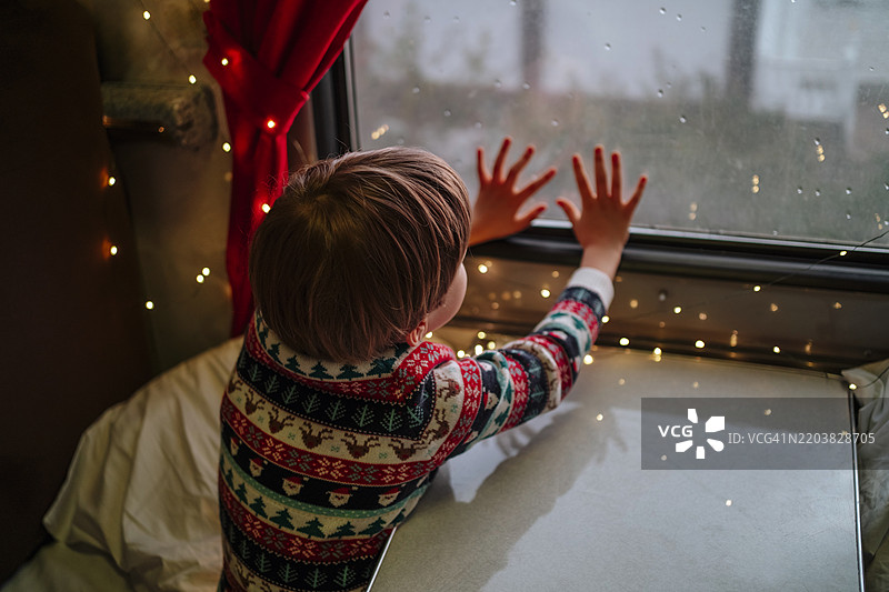男孩在圣诞节触摸装饰过的火车窗户图片素材