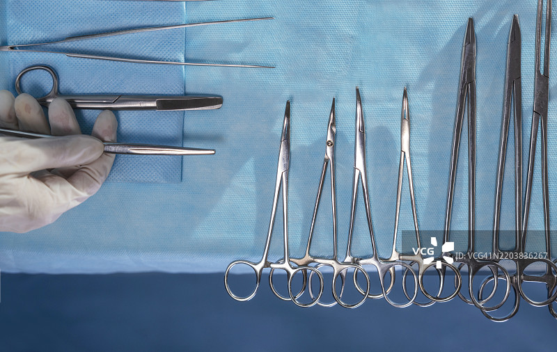 护士的手握着手术工具，靠近手术台上的剪刀图片素材