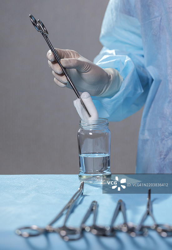 护士手持餐巾，手术工具悬在水中的罐子上图片素材