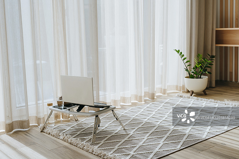 笔记本电脑放在家中地毯上的桌子上图片素材