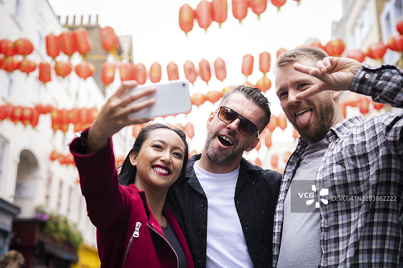 快乐的女人在街上用智能手机与朋友自拍图片素材