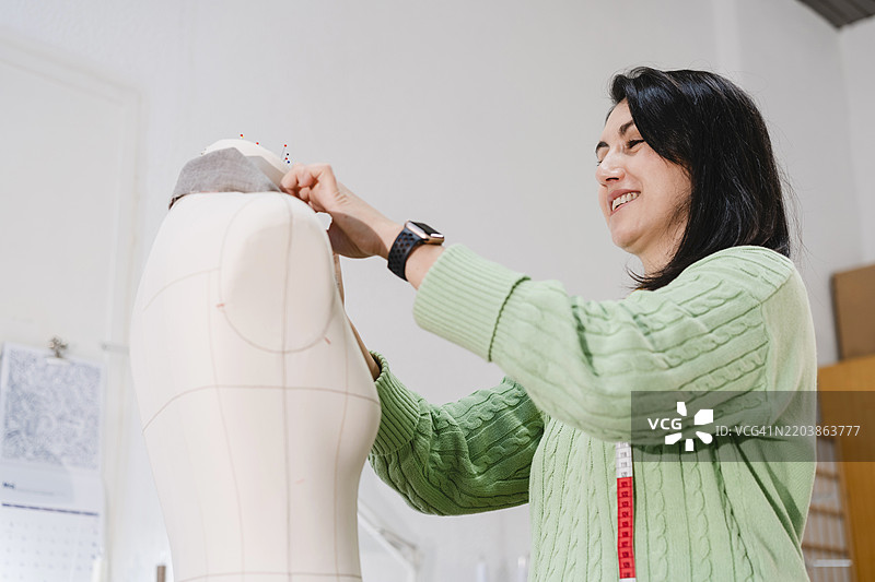 微笑的女性在工作坊中为假人模型工作图片素材