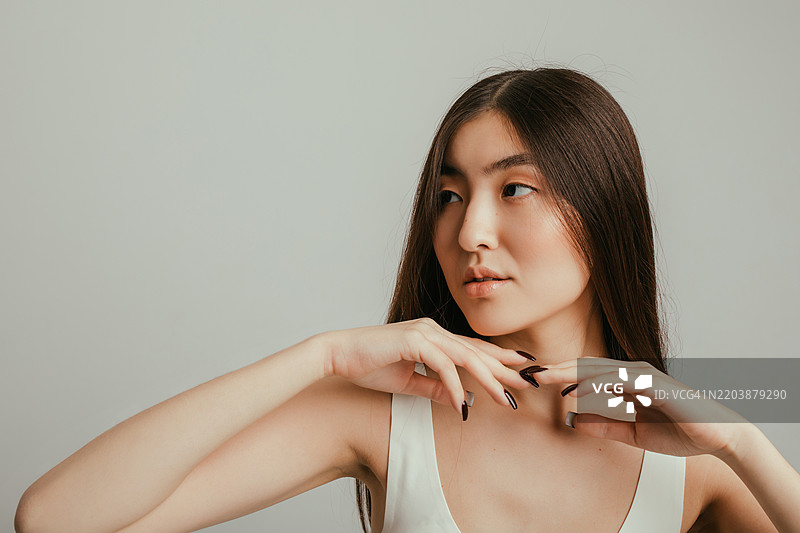 优雅的亚洲女性以优美的姿势摆姿势，背景中性图片素材