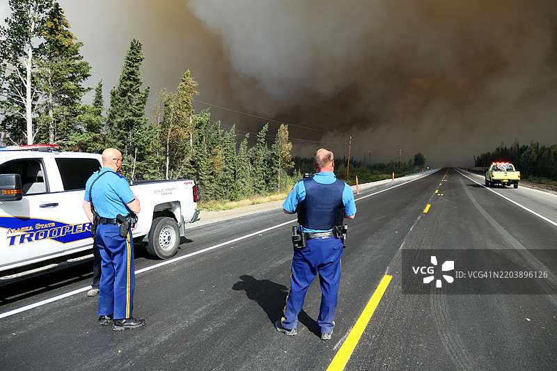 两名阿拉斯加州警察在阿拉斯加基奈国家野生动物保护区观察野外森林火灾烟雾穿过道路。图片素材