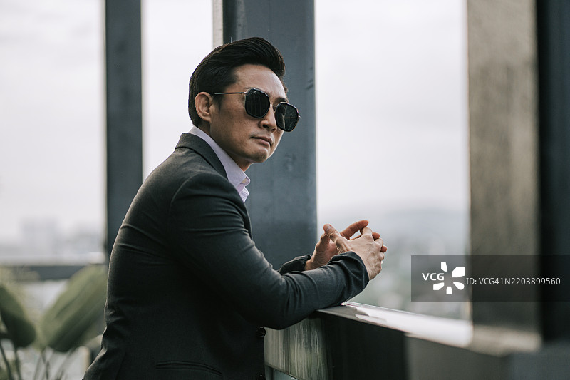 穿着西装的酷炫态度亚洲中国商人在屋顶上望向远方图片素材
