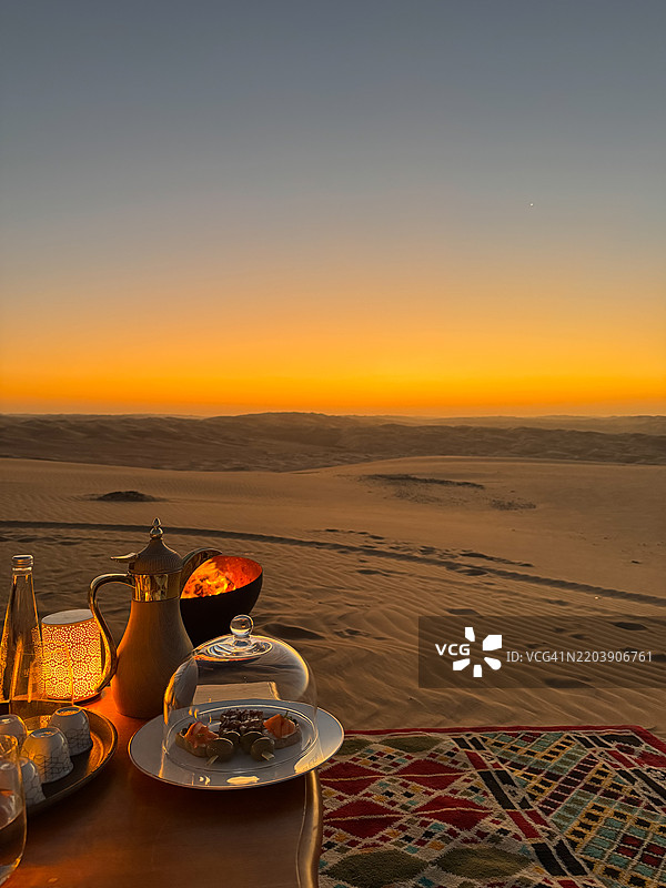 在阿布扎比利瓦沙漠沙丘附近，篝火旁享用小吃、开胃菜和咖啡，营造浪漫的日落时刻。图片素材