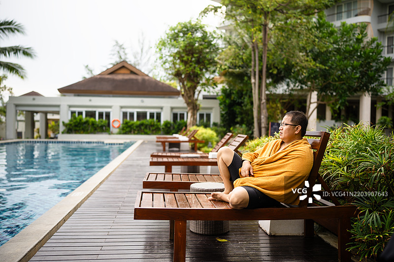 早晨，一个男人坐在游泳池里图片素材