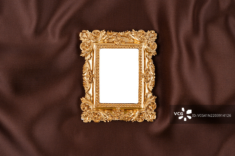 棕色丝绸背景上的空白金色相框。保存剪切路径。图片素材