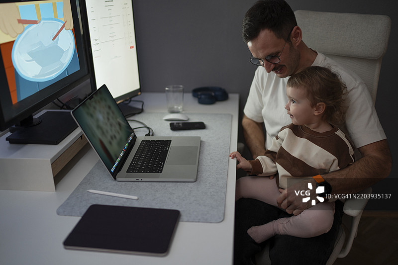 父亲在家工作，怀抱着他的女儿。图片素材