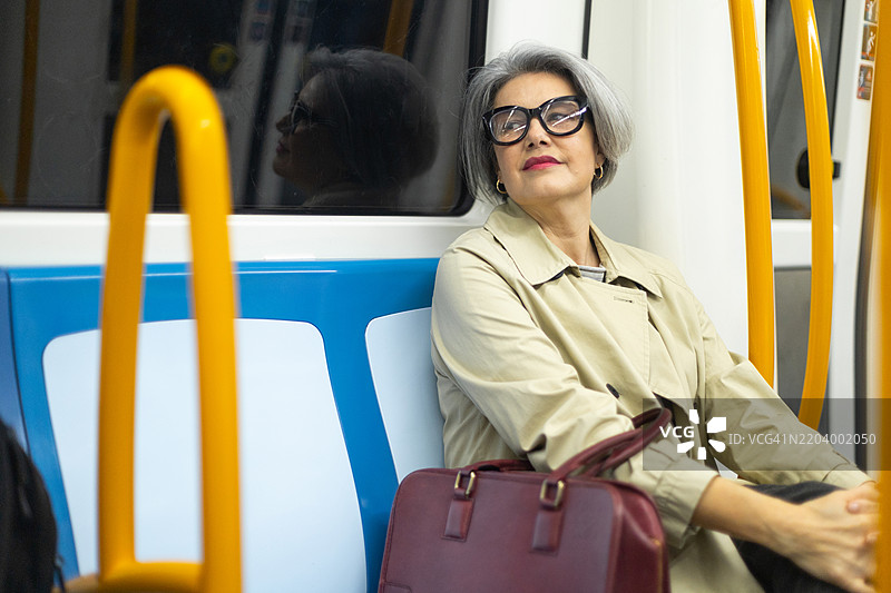 成熟的女商人在地铁上通勤，目光投向一旁图片素材