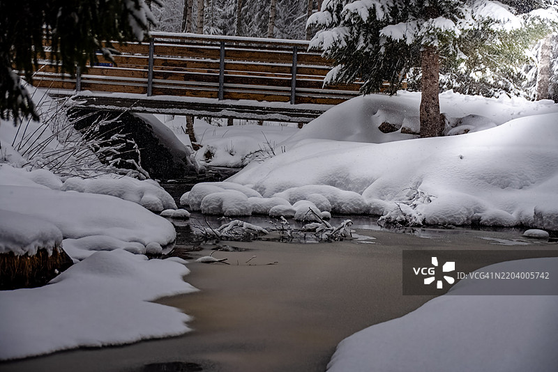 大雪纷飞，小湖被冰雪覆盖，岩石上也积满了雪。图片素材