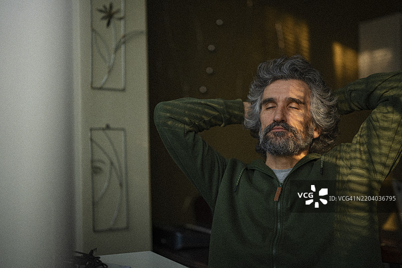 成熟的自由职业者在家中阳光下放松。远程工作图片素材