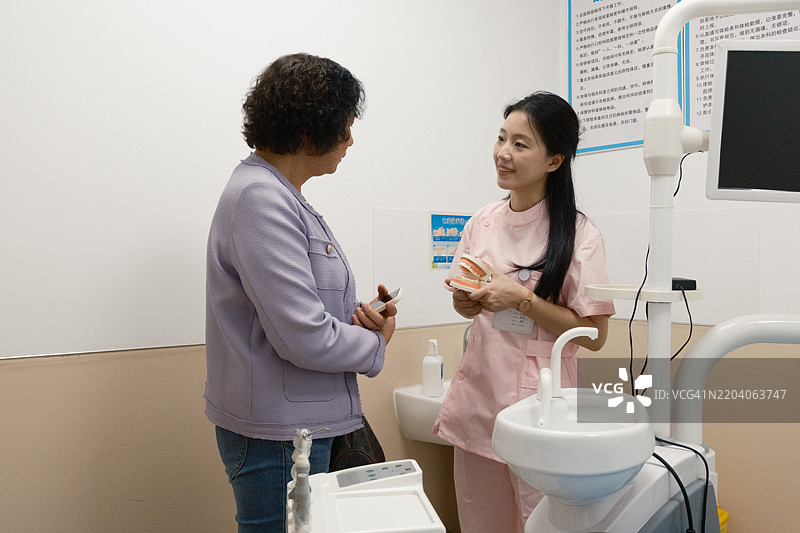 牙医使用牙齿模型向老年人介绍牙齿护理图片素材