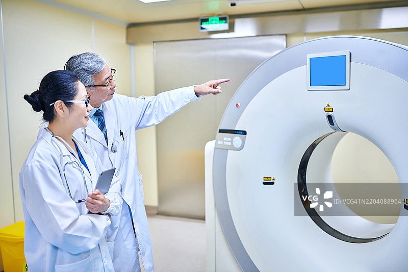 两位亚洲医生在MRI扫描室讨论和检查图片素材