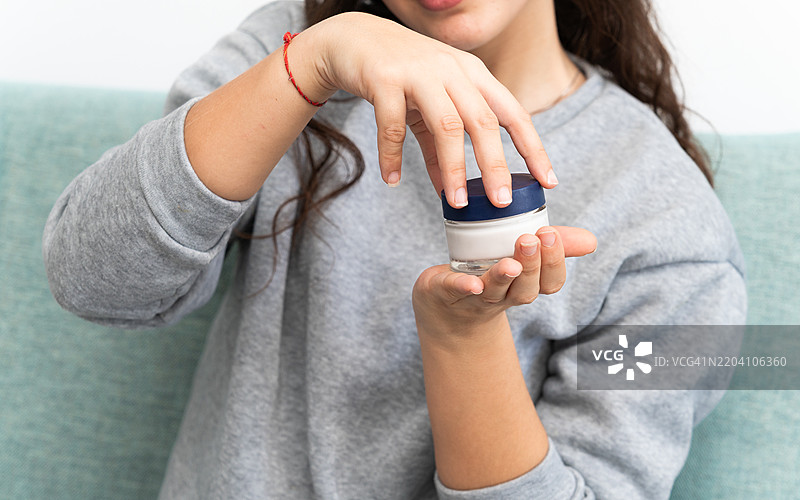 少女打开保湿霜瓶，进行护肤程序图片素材