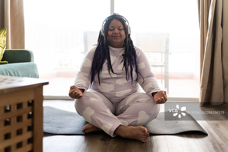 年轻女性在家中戴着耳机冥想图片素材