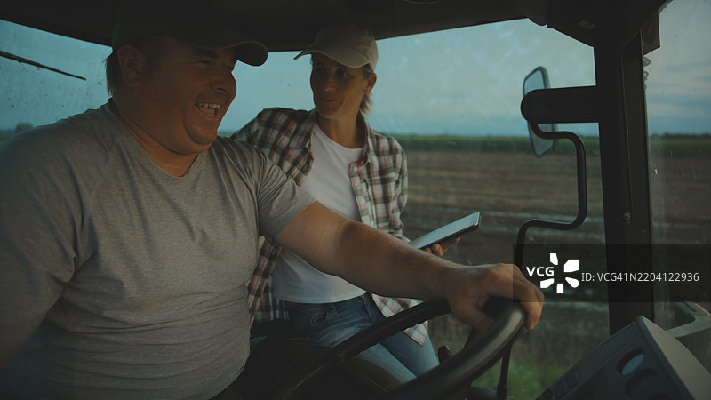 农民在拖拉机驾驶室里轻松地分享工作时光图片素材