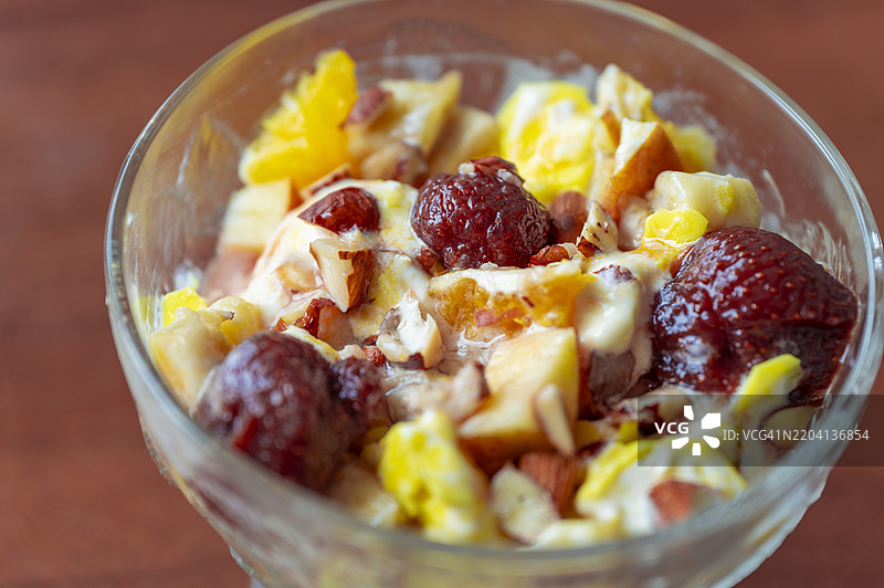 美味的甜点碗，里面有奶油冰淇淋、脆脆的坚果、甜美的樱桃酱，以及鲜艳的橙子和苹果片图片素材