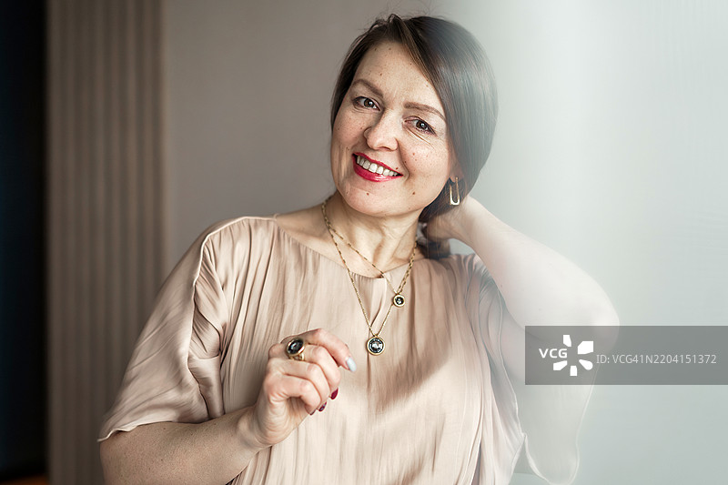 一位女性试图系紧链锁，佩戴珠宝。展现老年人的个性和风格。背面视角，中景拍摄。图片素材