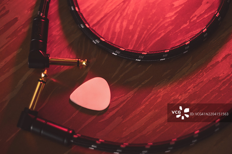 电吉他插头和拨片的电缆，放置在木质表面上图片素材