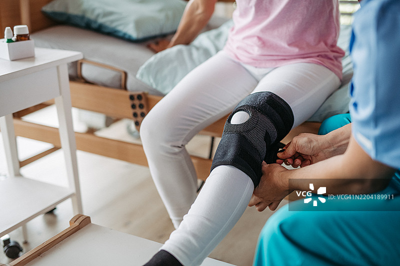 医生为女性患者提供膝盖支架。康复和物理治疗概念。图片素材