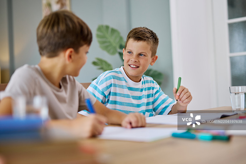两个兄弟一起做作业，微笑着聊天图片素材