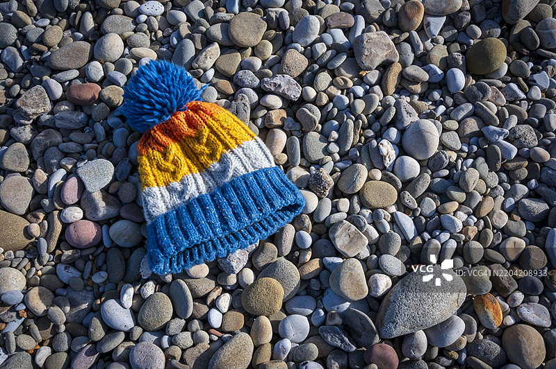 毛绒毛线帽放在海滩的卵石上图片素材