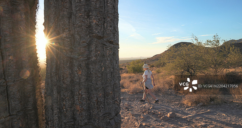 女人在日落时分的沙漠景观中徒步旅行图片素材