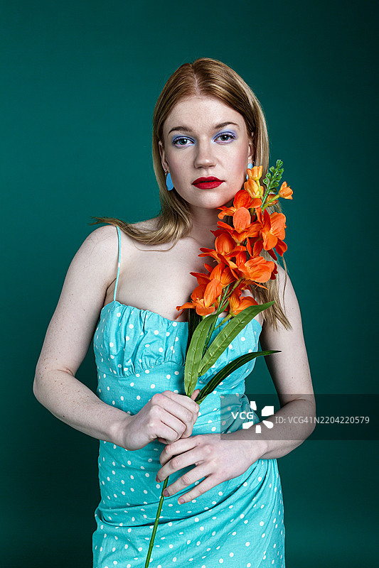 优雅的女性穿着夏季连衣裙，手捧一朵花图片素材