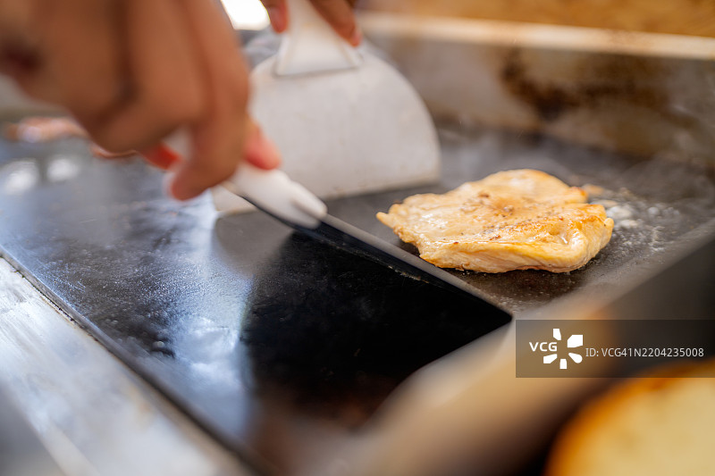 在自助餐厅中，厨师在热板上准备鸡胸肉图片素材