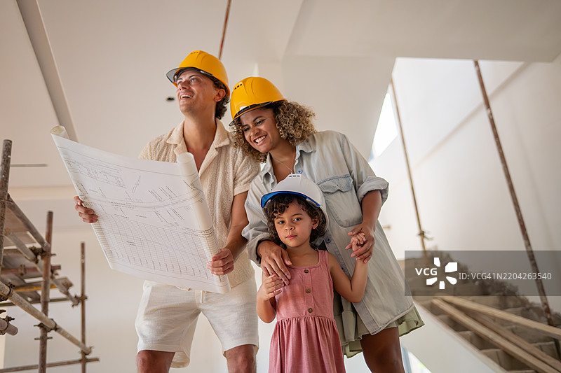 一家人在正在建设的多层建筑下兴奋地讨论蓝图，展望他们未来的家，规划和梦想拥有房屋，讨论这个空间未来的可能性，反映出一个重要的人生里程碑。图片素材