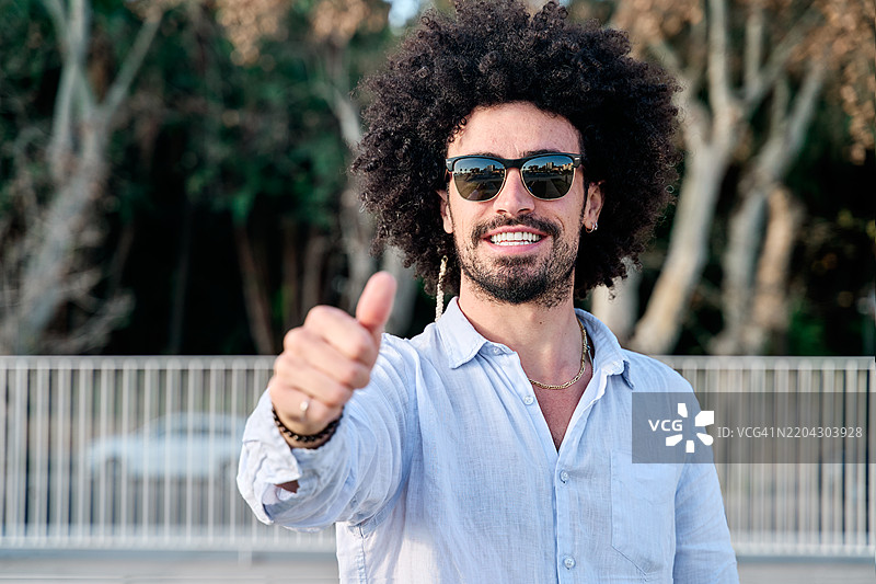 微笑并竖起大拇指的非洲卷发年轻男子图片素材