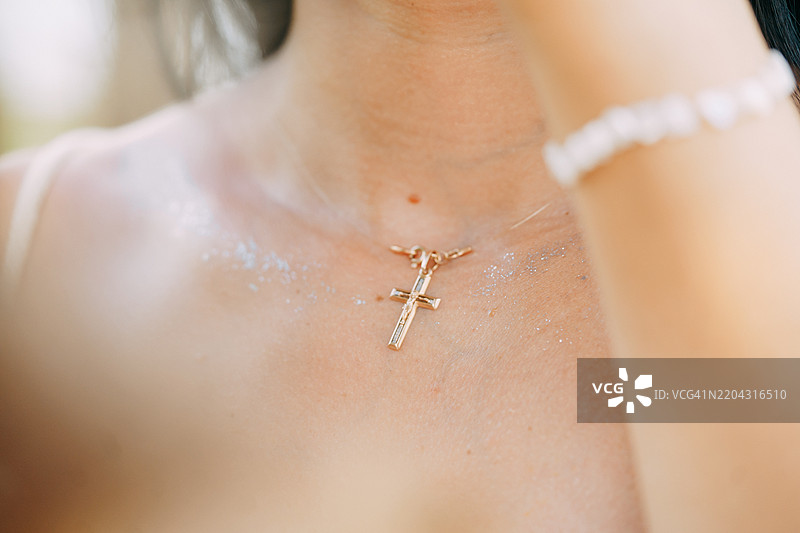 佩戴金色十字项链和闪光装饰的女性：灵性、宗教与时尚图片素材