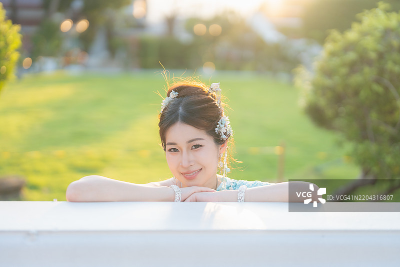 在泰国曼谷的黎明寺，穿着传统泰国服装的年轻亚洲女性在日落时分被拍摄。图片素材