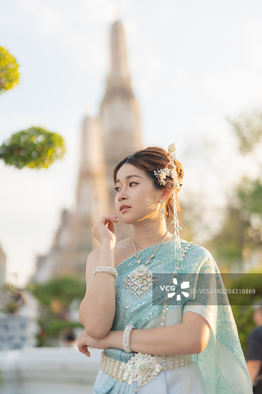 一位身穿传统泰国服饰的年轻泰国女性在泰国寺庙中。图片素材