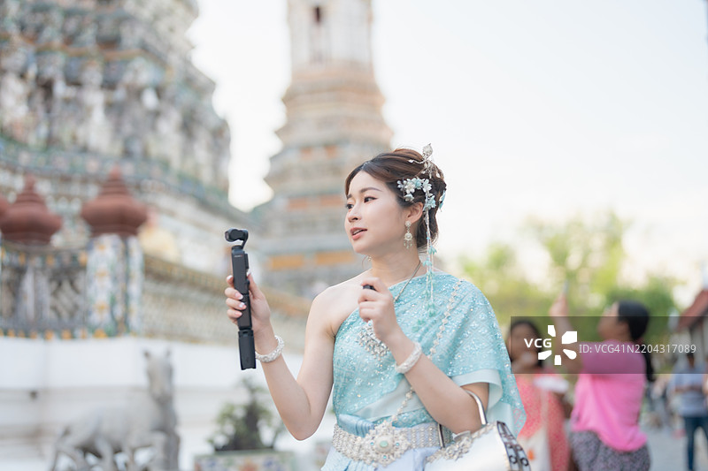在泰国曼谷旅游时，一位亚洲旅行博主身穿传统泰国服饰。YouTuber、内容创作者和影响者。图片素材