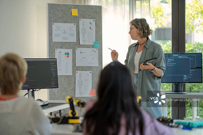 一组年轻工程师在为科学项目合作构建机器人原型，使用笔记本电脑进行编码和运行模拟。这种动手的STEM学习体验促进了创新、团队合作和机器人技术的专业知识。图片素材
