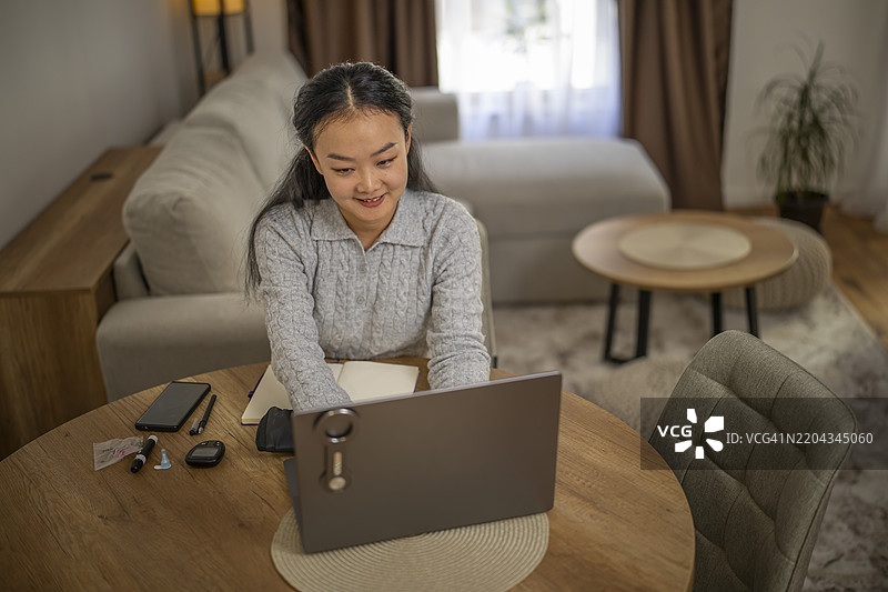 可爱的亚洲女性坐在餐厅的桌子旁上网。图片素材